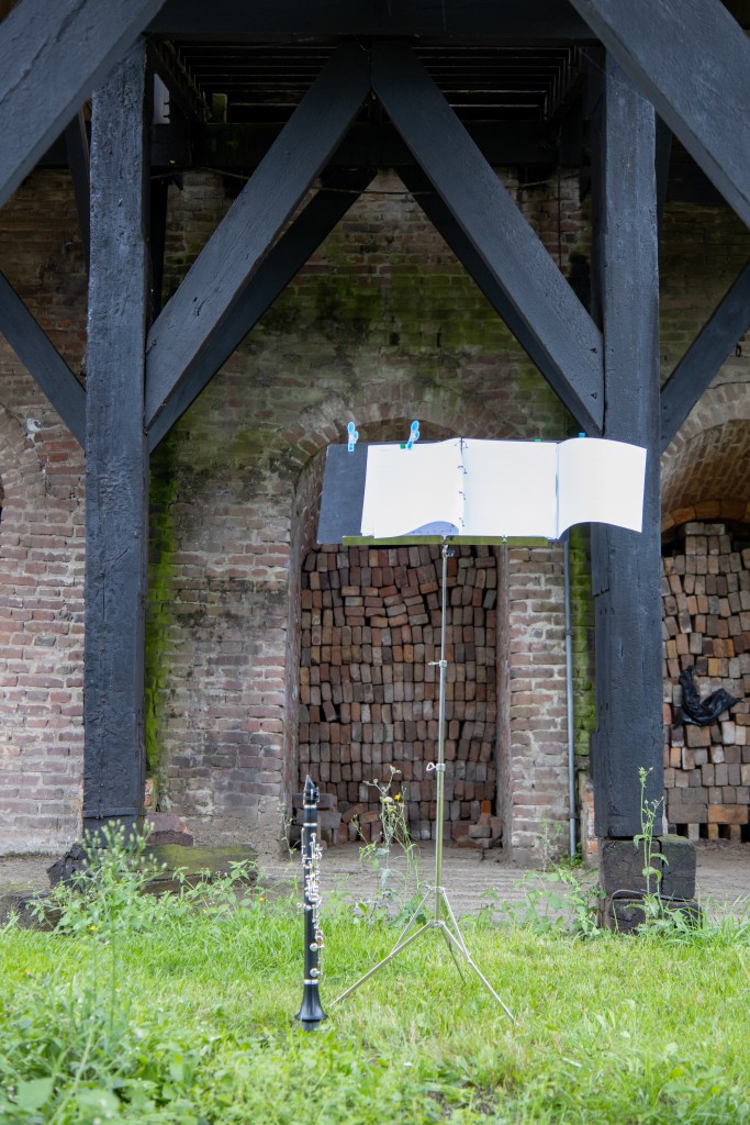 Een klarinet en lessenaar staan klaar in het gras voor de steenoven, voorafgaand aan de voorstelling