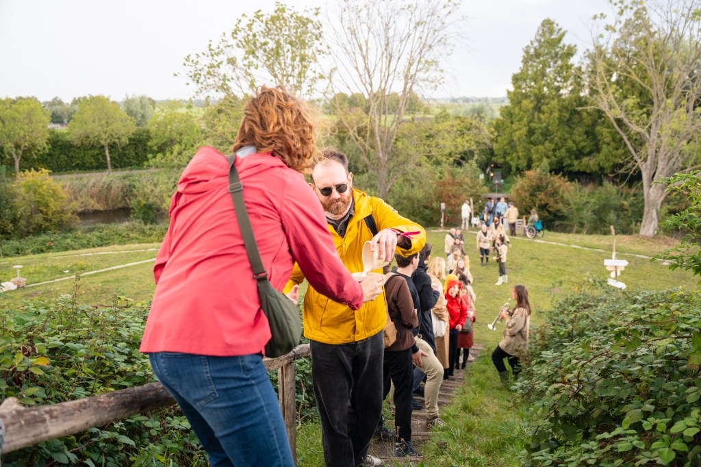een lange stoet mensen van onderaan naar de top van het fort. Vooraan giet een man water in een kopje van een vrouw